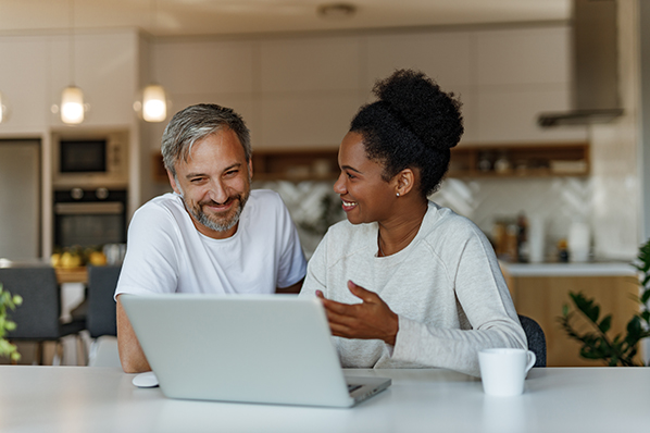 middle aged couple sitting at their kitchen island looking at the laptop